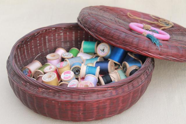 vintage round wicker sewing basket full of spools of colored cotton thread
