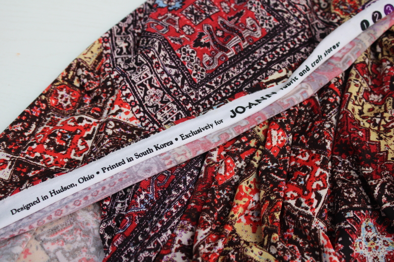 modern boho style slinky poly knit fabric, reds browns print patchwork of oriental rug patterns