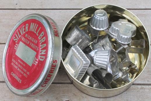 old cherry tin full of vintage cookie cutters, small jello molds, doughnut dropper