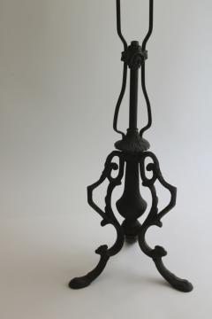 catalog photo of antique cast wrought iron lamp, ornate scrolled shape w/ original black finish 