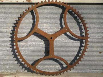 catalog photo of big old antique forged iron toothed gear wheel, steampunk machine age