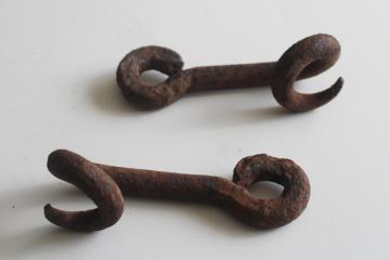 old hand forged iron pigtail hooks, rusty antique hardware rope guides from farm equipment 