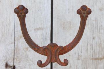 catalog photo of rusty old antique iron coat hook, ornate vintage cast iron hardware double hook
