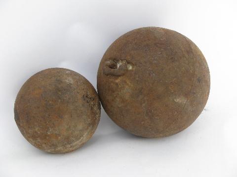 photo of two old antique iron balls, round weights or cannonballs #1